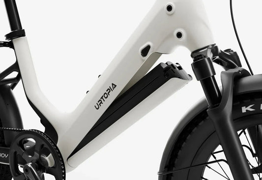 Side view of the Urtopia Carbon Joy eBike in a modern urban setting, showcasing its lightweight carbon frame, sleek design, and integrated display.