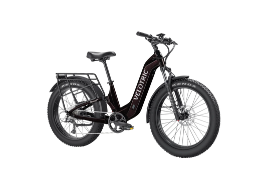 Side view of the Velotric Nomad 2X eBike in matte black, showing its fat tires, front suspension fork, integrated battery, and rear cargo rack.