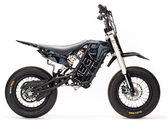 Stomp Ebox Megalith Graphics Kit displayed on a dirt bike, featuring bold geometric patterns in black, white, and neon yellow with the Stomp logo.