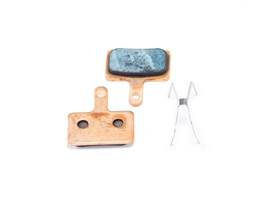 Close-up view of Stomp Ebox sintered brake pads showing metallic friction surface and backing plate on a white background.